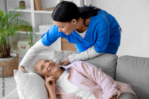 Female nurse caring about lying senior woman at home photo