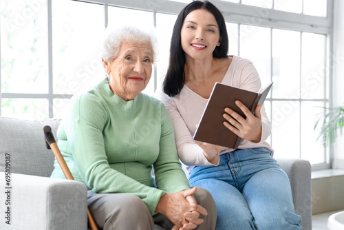 Senior woman and her daughter with book at home photo