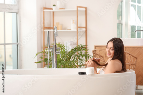 Young brunette woman applying hair product in bathroom