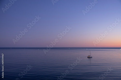 Beautiful sunset on the Atlantic Sea with sailboat in the foreground. Algarve Coast, Portugal