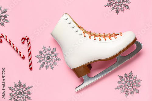 Ice skate with decorative snowflakes and candy canes on pink background photo