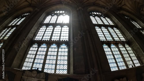 LOW ANGLE VIEW: Bright rays of sunlight shine through the magnificent window. Beautiful architectural details in every corner of the Canterbury Cathedral. Stunning religious and historical monument. photo
