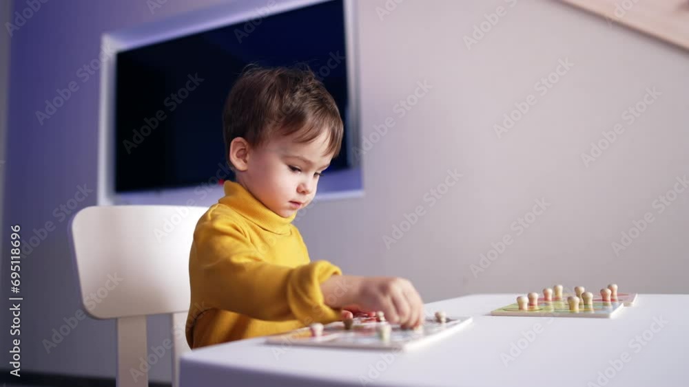 Attentive cute baby boy playing with his puzzles at desk. Lovely toddler studying through the game. Attentive cute baby boy playing with his puzzles at desk. Lovely toddler studying through the game.