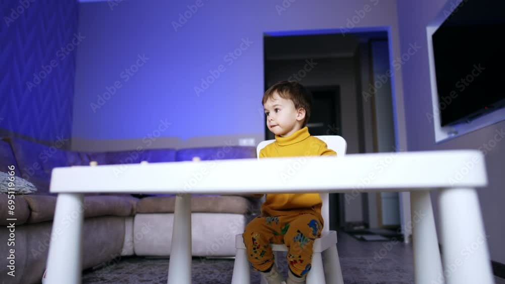 Beautiful Caucasian toddler boy sitting at white desk. Lovely baby at home. Low angle view. Beautiful Caucasian toddler boy sitting at white desk. Lovely baby at home. Low angle view.