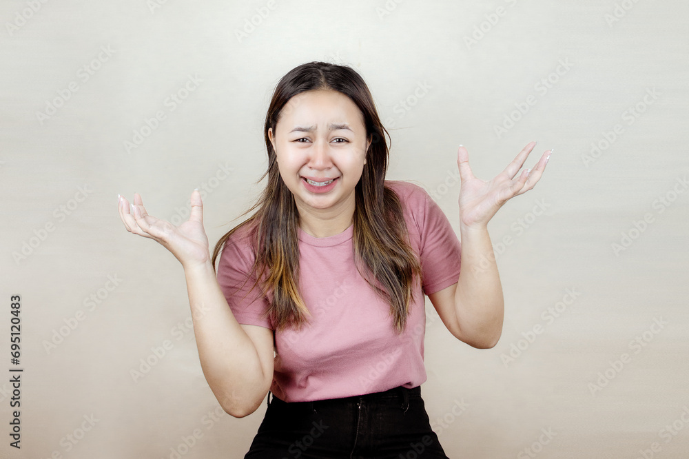 Beautiful young Asian woman crying feeling very depressed isolated on blue background screaming loudly Beautiful young Asian woman crying feeling very depressed isolated on blue background screaming loudly