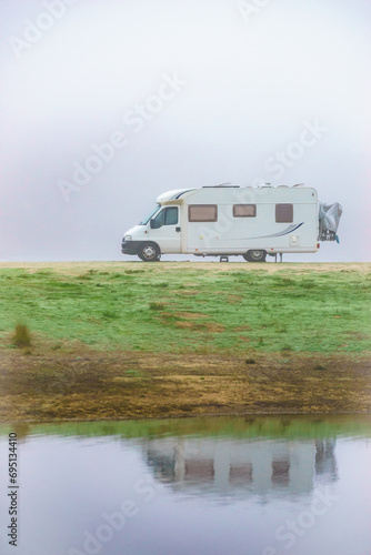 Camper rv camping at lake shore. Foggy day