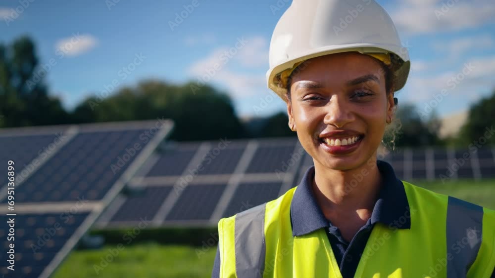 Close up portrait of female engineer wearing hard hat and hi vis safety vest outdoors inspecting solar panels on sustainable energy farm - shot in slow motion Close up portrait of female engineer wearing hard hat and hi vis safety vest outdoors inspecting solar panels on sustainable energy farm - shot in slow motion