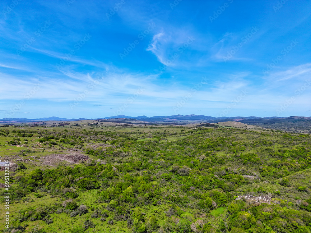 Aerial view taken by drone of a field with bright vegetation and small mountains Aerial view taken by drone of a field with bright vegetation and small mountains