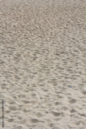 Close image of sand with several footprints marked