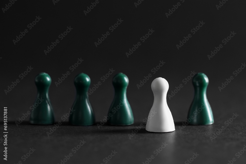 Choice concept. White pawn and green ones on dark table, closeup Choice concept. White pawn and green ones on dark table, closeup