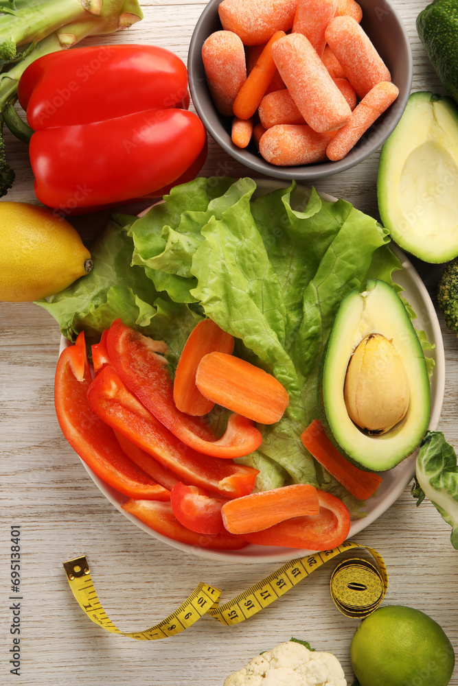 Healthy diet. Fresh vegetables and measuring tape on light wooden table, flat lay Healthy diet. Fresh vegetables and measuring tape on light wooden table, flat lay