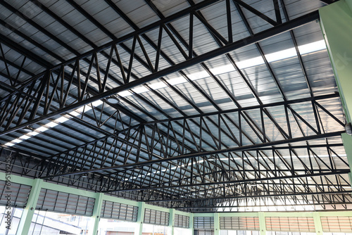 Metal roof structure. Detail of black steel roof structure of warehouse with illuminated tiles in selective focus.