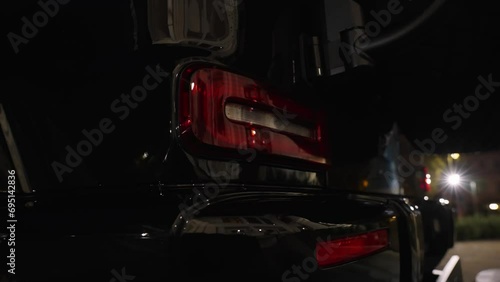 Yellow rear turn indicator blink on shiny black Mercedes G Wagon car photo