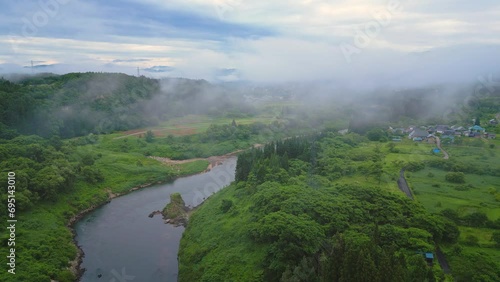 Slowly flying through low hanging clouds in the Fukushima prefecture of Japan, river in stunning green landscape. photo