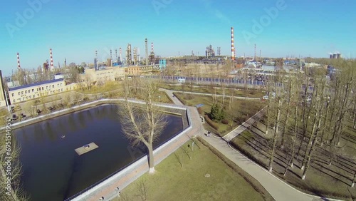 Small pond in park near oil refinery in sunny spring day photo