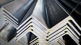 Stacks of angle iron in a factory on shelves in a warehouse Metal profile corners in packs Equal angle steel, angle steel, metal profile angles in packs at the metal products warehouse.