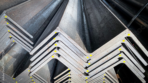 Stacks of angle iron in a factory on shelves in a warehouse Metal profile corners in packs Equal angle steel, angle steel, metal profile angles in packs at the metal products warehouse. photo