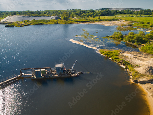 Suction dredger vessel works drawing up bottom mud on river photo
