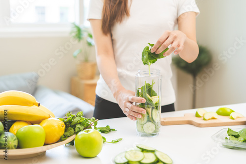 Vegetable smoothie detox, woman hand making healthy raw fresh green fruit juice with blender machine, preparing drink with spinach in kitchen at home, eating vegan diet. Healthy dieting, weight loss. photo