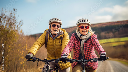 retired couple  wearing warm clothes  helmets and sunglasses  riding a bicycle in nature  as part of an adventure trip for seniors