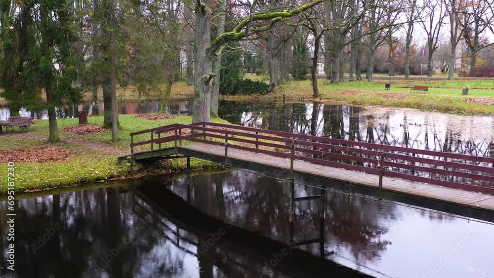 Wooden bridge in park over a pond in late autumn on a gloomy day Wooden bridge in park over a pond in late autumn on a gloomy day