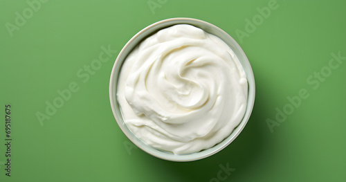 Top view of bowl with white quark or cream on side of green background with copy space photo