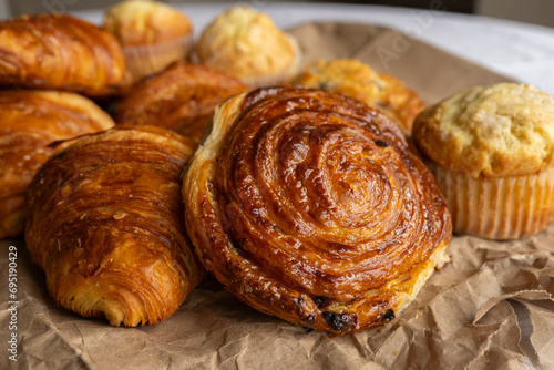 Charming tableau of a basket filled with French pastries on a table. Croissants and puff pastry layers nestle in the basket, evoking a delightful scene of baked indulgence.