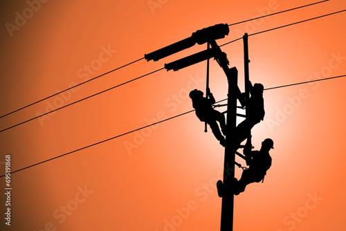 The silhouette of lineman are replacing damaged insulator insulators by using insulated wire-tong sets, tie stick and robe box sets in sliding wires going out in a safety working distance. photo