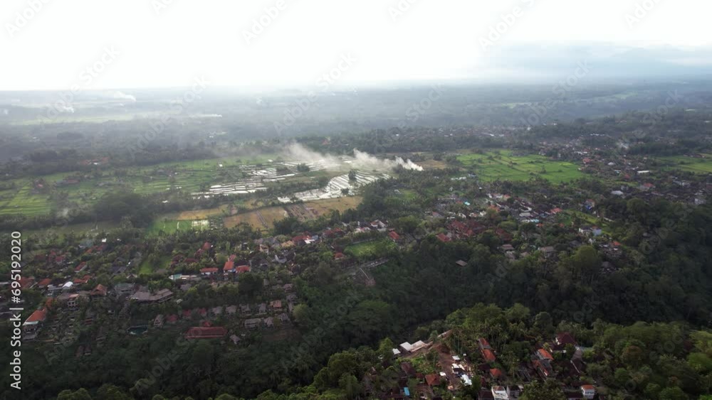 Aerial view of west Ubud, Raya Sanggingan street seen down, rice fields at distance. Smoke from burning straw at harvested plantations rise up in air. Typical countryside around Ubud town Aerial view of west Ubud, Raya Sanggingan street seen down, rice fields at distance. Smoke from burning straw at harvested plantations rise up in air. Typical countryside around Ubud town