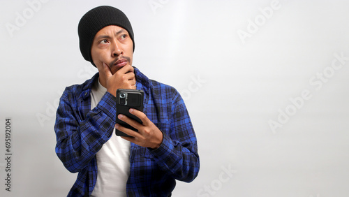 Foto A puzzled and confused Asian man, dressed in a beanie hat and casual shirt, reac