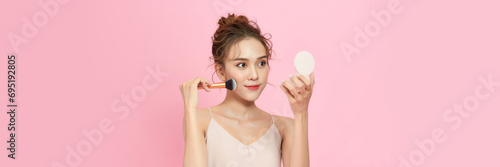 Young woman applying make-up from powder compact.