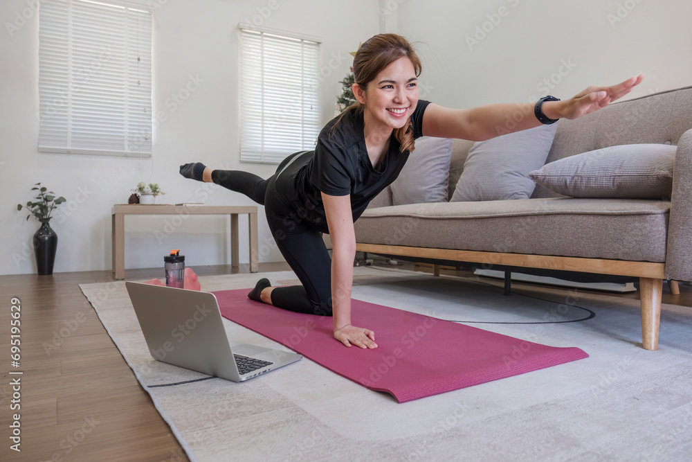 Young Asian sporty fitness woman coach do practice video online training yoga laptop in living room at home Young Asian sporty fitness woman coach do practice video online training yoga laptop in living room at home