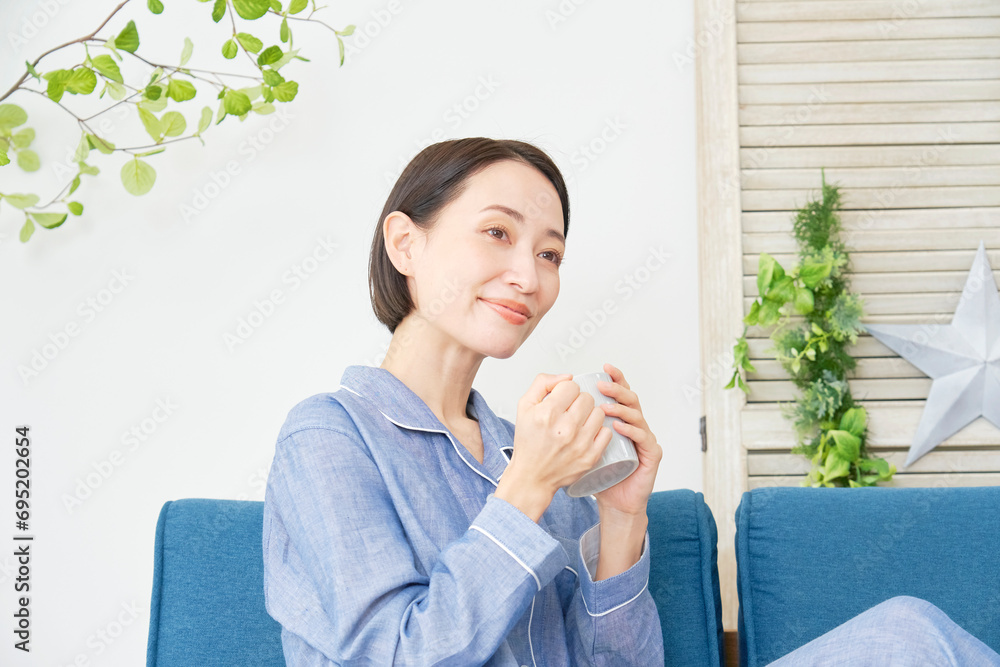 自宅でパジャマを着てマグカップを持って寛ぐ中年女性