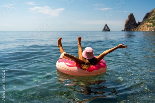 Summer vacation woman in hat floats on an inflatable donut mattress. Happy woman relaxing and enjoying family summer travel holidays travel on the sea.