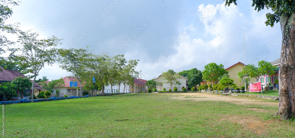Natural View Of The School Yard With Green Grass And Several Buildings During The Day