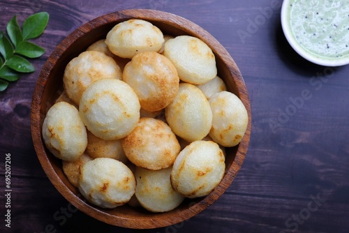 Paniyaram are savory balls made using fermented rice and urad dal batter along with tempered onion and spices. Also known as Paddu, Ponganalu, Kuli, bugga, and appe. served with coconut chutney photo