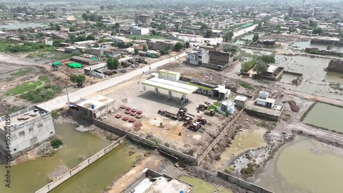 Aerial circular shot of a fuel pump in rural Badin, Sindh, amidst buildings and water. photo