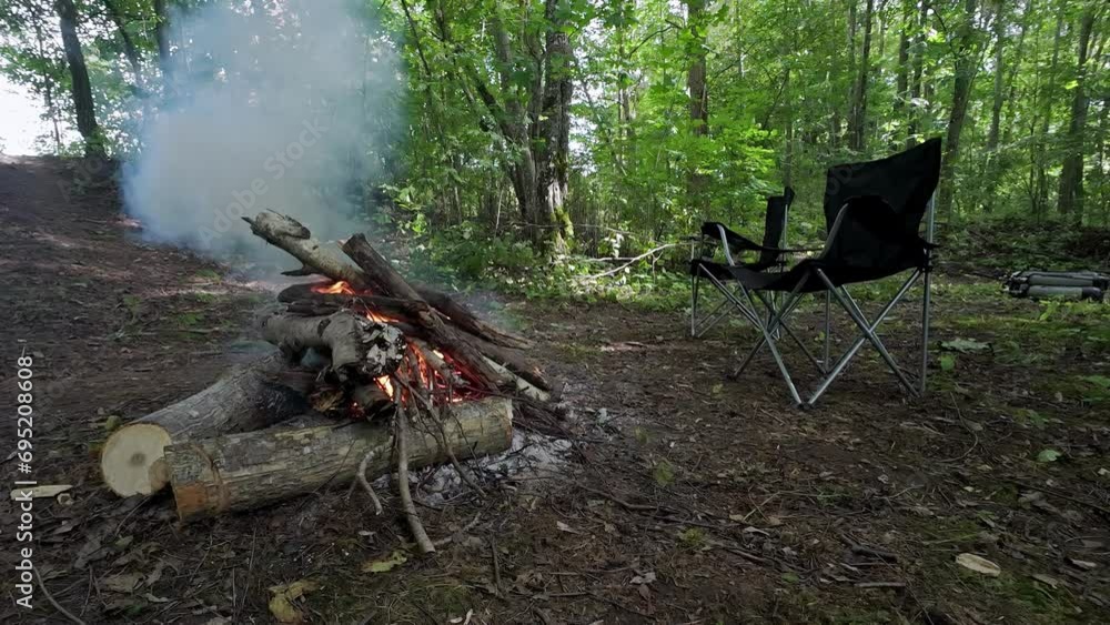 A Stack Of Woods On Fire At An Open Area Surrounded By Trees With A Camping Chair A Stack Of Woods On Fire At An Open Area Surrounded By Trees With A Camping Chair