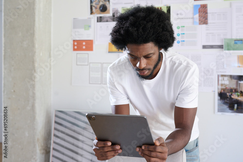 Focused Digital Workflow. Black man attentively using a tablet in a design studio. photo