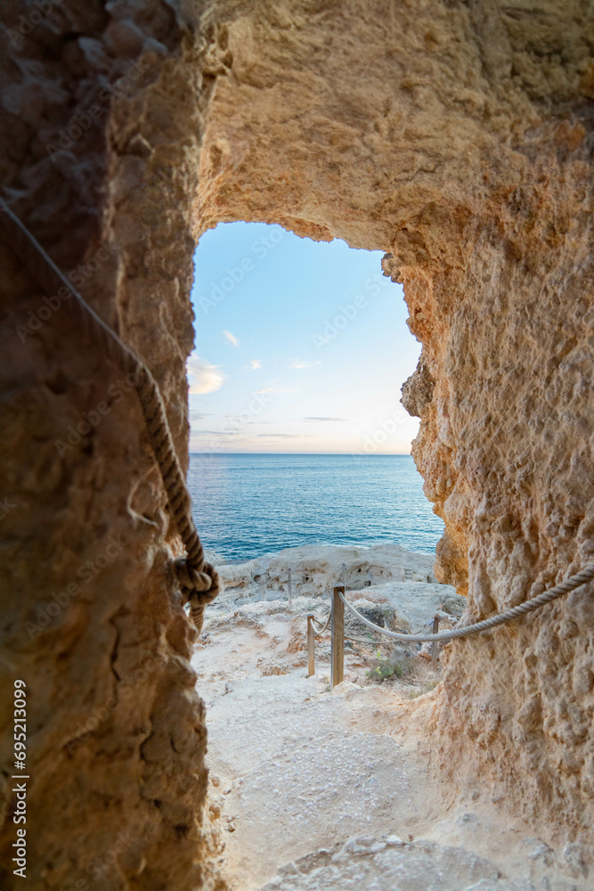 A Glimpse of Serenity: A Low-Angle, Vertical View from Inside a Cave in Portugal, Overlooking the Tranquil Atlantic ocean Under the Clear Blue Sky, 