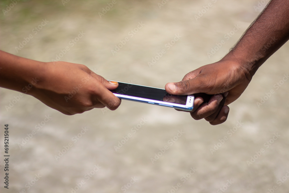 Two people holding a mobile by hand and blurred background