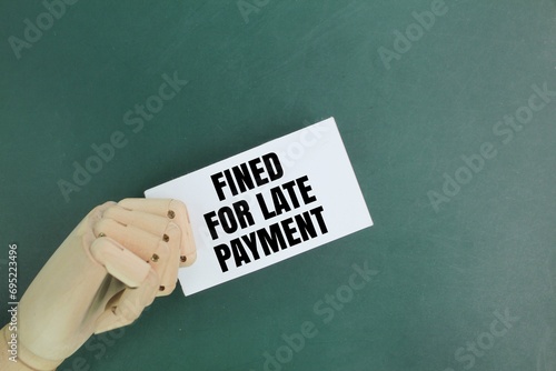 hand holding a white paper with the word fined for late payment. the concept of fined or penalty photo