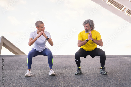 senior sports man doing a squat workout with his personal trainer to have strong legs, concept of active and healthy lifestyle in middle age