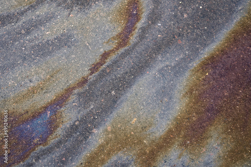 Textured stain of fuel or oil on wet asphalt on a rainy day