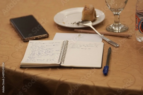Books, pens, cellphones and cakes lay on the table. Just above the shot of the object on the table