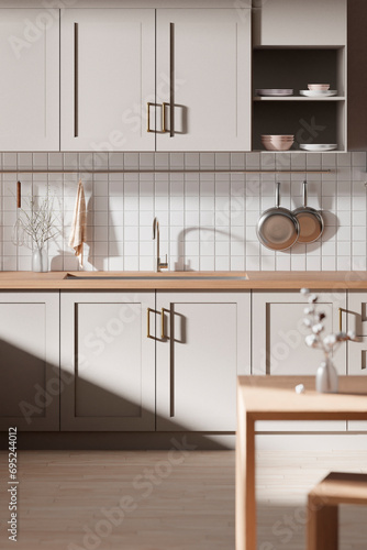 A bright beige-toned kitchen interior with sunlight 
coming through the window.