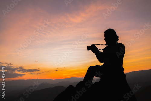 Silhouette of a photographer on top of a mountain at sunset