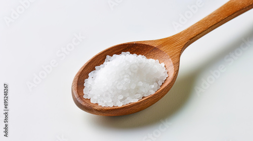 The sea salt is isolated in a wooden spoon on a light background