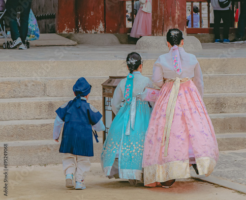 Photography Asian family wearing a beautiful hanbok (the Korean traditional dress) entering in the old Gyeongbokgung Palace in Seoul city, South Korea