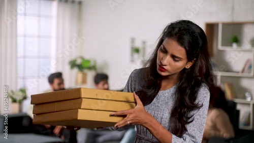 Happy Girl receiving pizza boxes from delivery person at home during friends home gathering at home - concept of weekend holidays, online food order and fast delivery photo